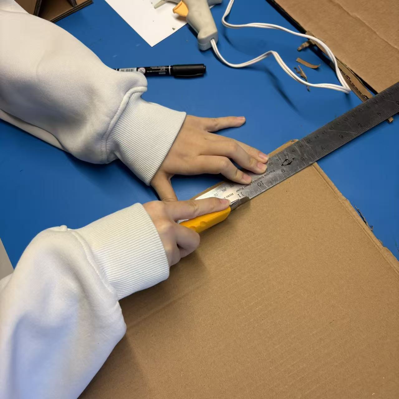 Using a ruler and utility knife to cut cardboard with clean edges.